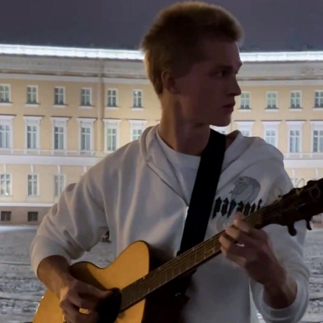 Андрей играет на акустической гитаре на Дворцовой площади вечером